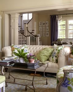 a living room filled with furniture and lots of green plants on top of the couch