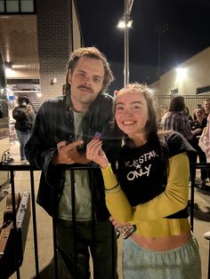 a man standing next to a woman near a fence