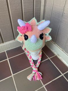 a crocheted stuffed animal with a pink bow on it's head sitting on a tile floor