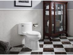 a white toilet sitting in a bathroom next to a cabinet