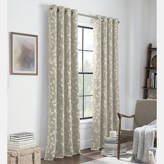 a living room with a chair and window covered in white curtain panels, along with a rug on the floor