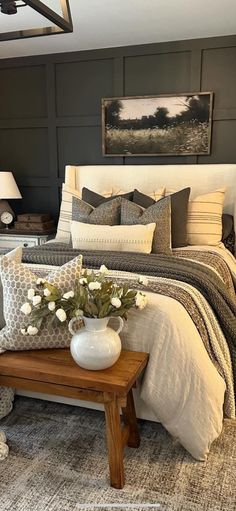 a bedroom with a bed, table and flowers on the end tables in front of it