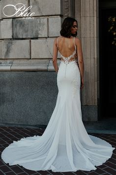 a woman in a white wedding dress standing on the street with her back to the camera