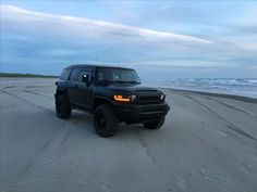 a black vehicle is parked on the beach