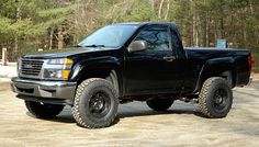 a black pick up truck parked in front of some trees