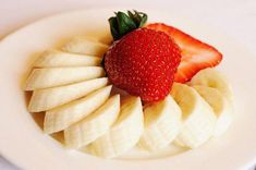 a white plate topped with sliced bananas and a strawberry