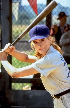 a woman holding a baseball bat on top of a field