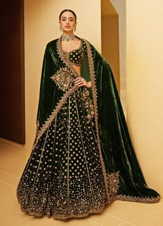 Introducing the stunning Emerald Green Embroidered Velvet Lehenga, a perfect blend of traditional elegance and contemporary charm. Crafted from luxurious velvet fabric, this lehenga is embellished with intricate zardosi and sequin embroidery, exuding a regal and opulent feel. The embroidered tassels on lehenga add to the bridal look. Paired with a matching blouse that mirrors the ornate design and completed with a beautifully bordered dupatta with a flowing drape, this lehenga set is a true statement piece. Ideal lehenga for a bride or bride-to-be on her Sangeet or Mehendi event. Composition : Blouse, Lehenga and Dupatta - Velvet Care: Dry Clean Only and Vacuum Storage This product can be customized for sleeves, blouse length and neckline Delivery : 6-8 weeks as the product is hand crafted Emerald Green Wedding Lehenga, Green Wedding Lengha, Velvet Lehenga Designs, Green Velvet Lehenga, Emerald Green Lehenga, Mehendi Event, Indian Wedding Dress Traditional, Wedding Outfits For Women, Blouse Lehenga