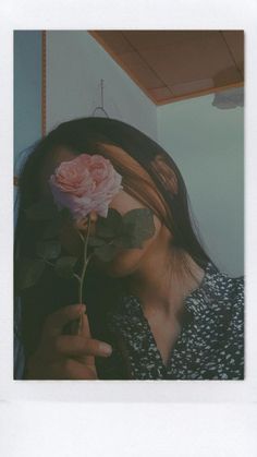 a woman holding a pink rose up to her face