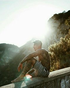 a man sitting on top of a stone wall