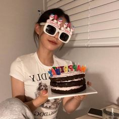 a woman holding a birthday cake with candles in her eyes while wearing sunglasses and reading glasses