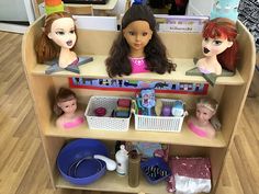 three dolls sitting on top of a shelf in a playroom with toys and other items