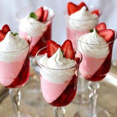 four desserts with strawberries and whipped cream in small glasses on a silver tray