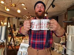 a man holding up a coffee mug with the words hobbyy lodger on it