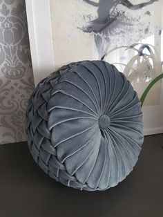 a large gray pillow sitting on top of a black table next to a framed photo