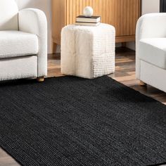 a living room with two white chairs and a black rug