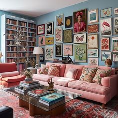 a living room filled with pink couches and lots of framed pictures on the wall