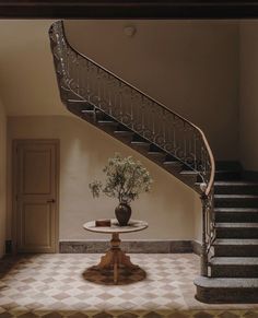 a vase with flowers sitting on top of a table next to a stair case