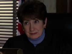 a woman sitting at a desk with a laptop computer in front of her and an american flag behind her