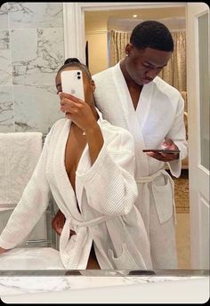 a man taking a selfie with his cell phone in the bathroom while wearing a robe