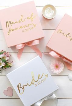 two pink and gold wedding guest books with matching bows on them, next to flowers