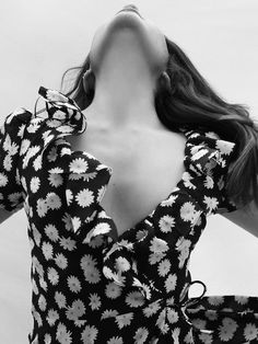 black and white photograph of a woman with her hands behind her head, wearing a floral top