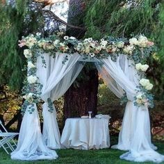 an outdoor wedding set up with white drapes and flowers