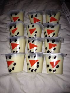 six cups with black dots and red triangle on them sitting on a white bed sheet