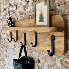 a wooden shelf with three hooks on it and a black purse hanging from the wall