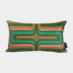 a green, pink and brown pillow with an abstract design on the front in black