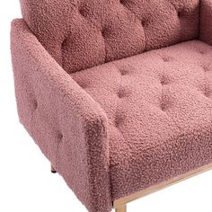 a pink chair with wooden legs and buttons on it's armrests is shown in front of a white background