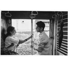 black and white photograph of two people standing on a train looking out the window at each other