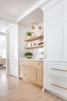 a kitchen with white cabinets and wooden floors, gold trim on the upper cabinet doors