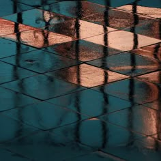 the reflection of an umbrella and its reflection in a puddle on a tiled floor,