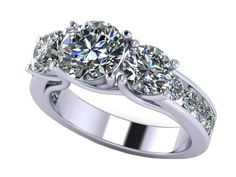 three stone engagement ring with side stones on the band and two round diamonds in the center