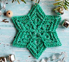 a green crocheted star ornament sitting on top of a wooden table