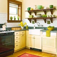 a kitchen with yellow cabinets and green dishes on the shelves above the stove, along with a red area rug