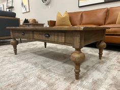 a coffee table with two drawers on it in front of a couch and clock hanging on the wall