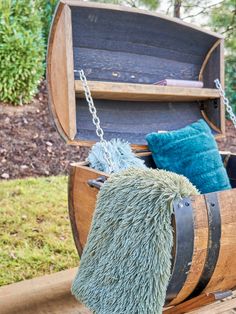 a wooden barrel with some blue and green pillows hanging from it's sides on a wood platform