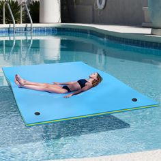 a woman laying on an inflatable mat next to a swimming pool