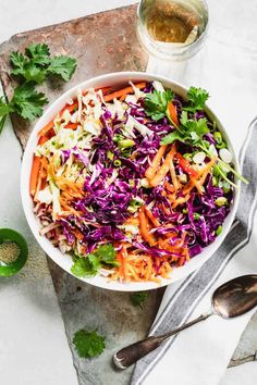 a bowl filled with coleslaw and carrots on top of a cutting board