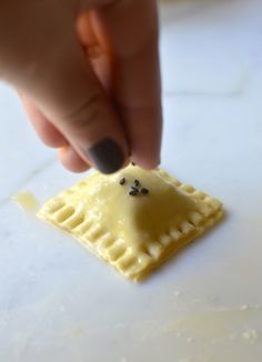 a hand is picking up some food from a small piece of pastry on a table