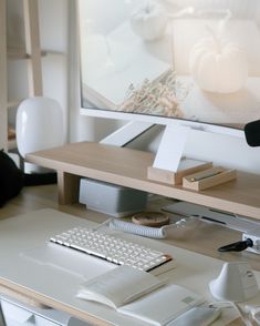 a computer desk with a keyboard, mouse and phone on it in front of a large screen