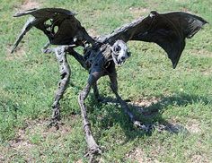 an animal made out of tree branches in the grass with its wings spread wide open