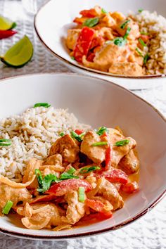 two white bowls filled with rice, meat and veggies on top of a table