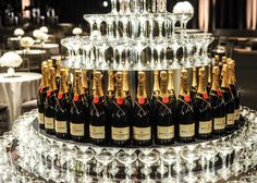 there are many bottles of champagne on the cake stand in front of wine glasses and plates