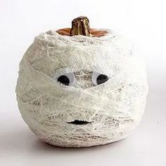 a white pumpkin with googly eyes and yarn wrapped around it