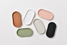 four oval trays with different colors and shapes on white surface, one is empty