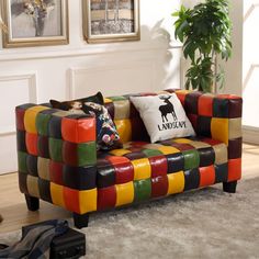 a multicolored couch sitting on top of a rug next to a potted plant