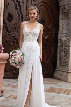 a woman standing in front of a door wearing a white dress and holding a bouquet